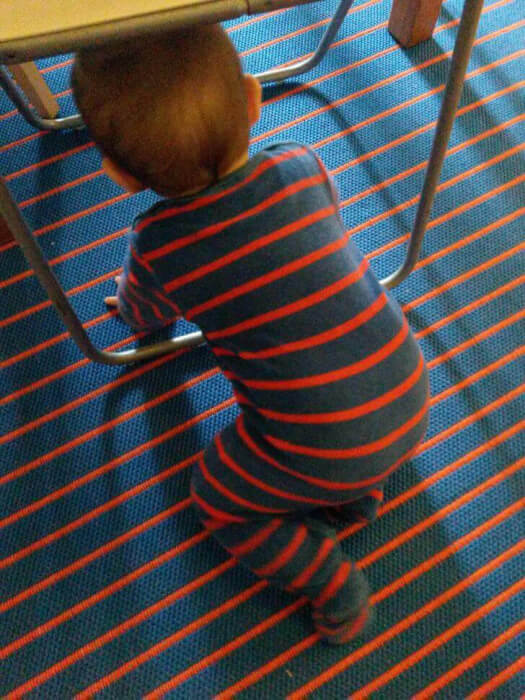 people match surroundings - baby wearing striped onsie matches rug